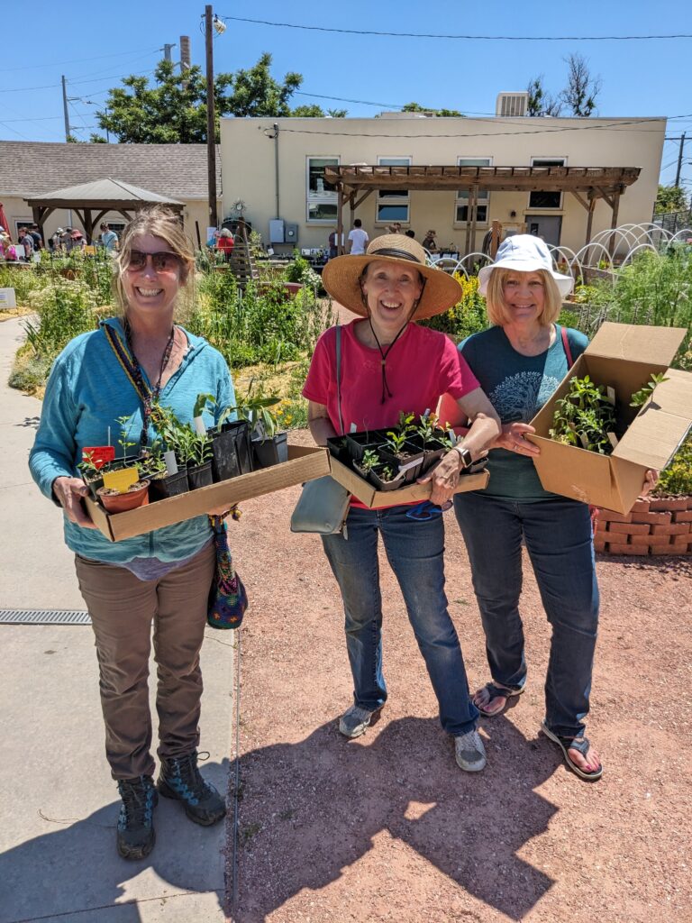 Three women with boxes of Colorado native plants they picked out at the Denver Plant Swap & Giveaway.