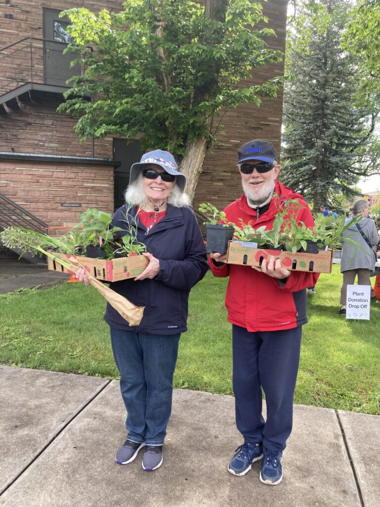 Woman and man holding boxes packed with Colorado native and pollinator plants in Fort Collins